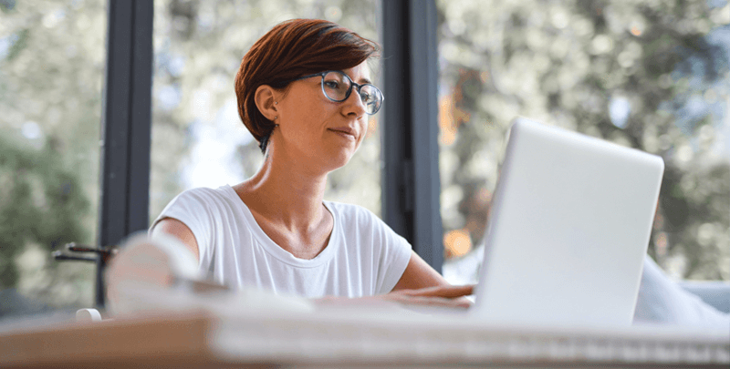 Dinâmica de trabalho remoto com mulher usando laptop em ambiente de escritório.