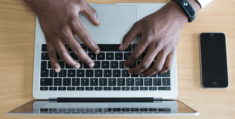 Profissional utilizando laptop e smartphone, foco em tecnologia e gestão financeira para contabilidade e assessoria tributária.