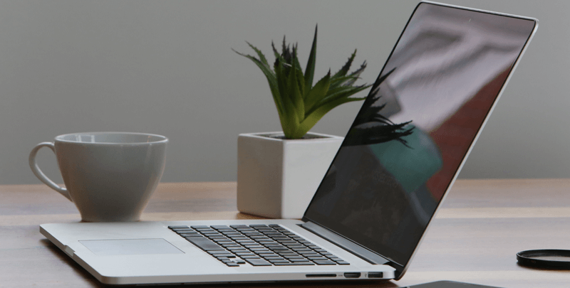 Ficheiro otimizado para SEO, ambiente de trabalho com laptop, planta e xícara de café, destacando eficiência administrativa e tecnologia.