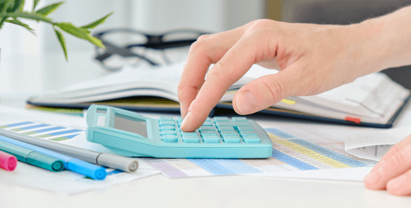 Calculadora financeira sobre documentos fiscais com canetas coloridas, representando soluções fiscais e contábeis.