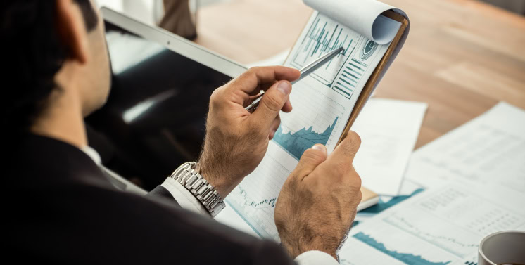 Relatório financeiro com gráficos de crescimento, análise de dados, tablets e papéis, indicando serviços de assessoria fiscal e tributária da Dootax no Brasil.