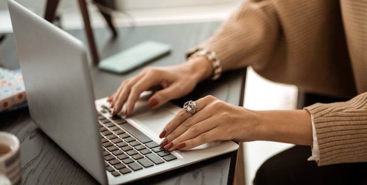 Notebook no escritório, uma mulher branca está digitando nele.